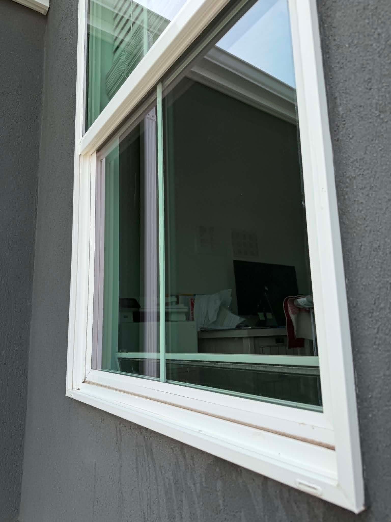 A freshly cleaned exterior window on a grey stucco home in Utah County — streak-free glass, no hard water spots